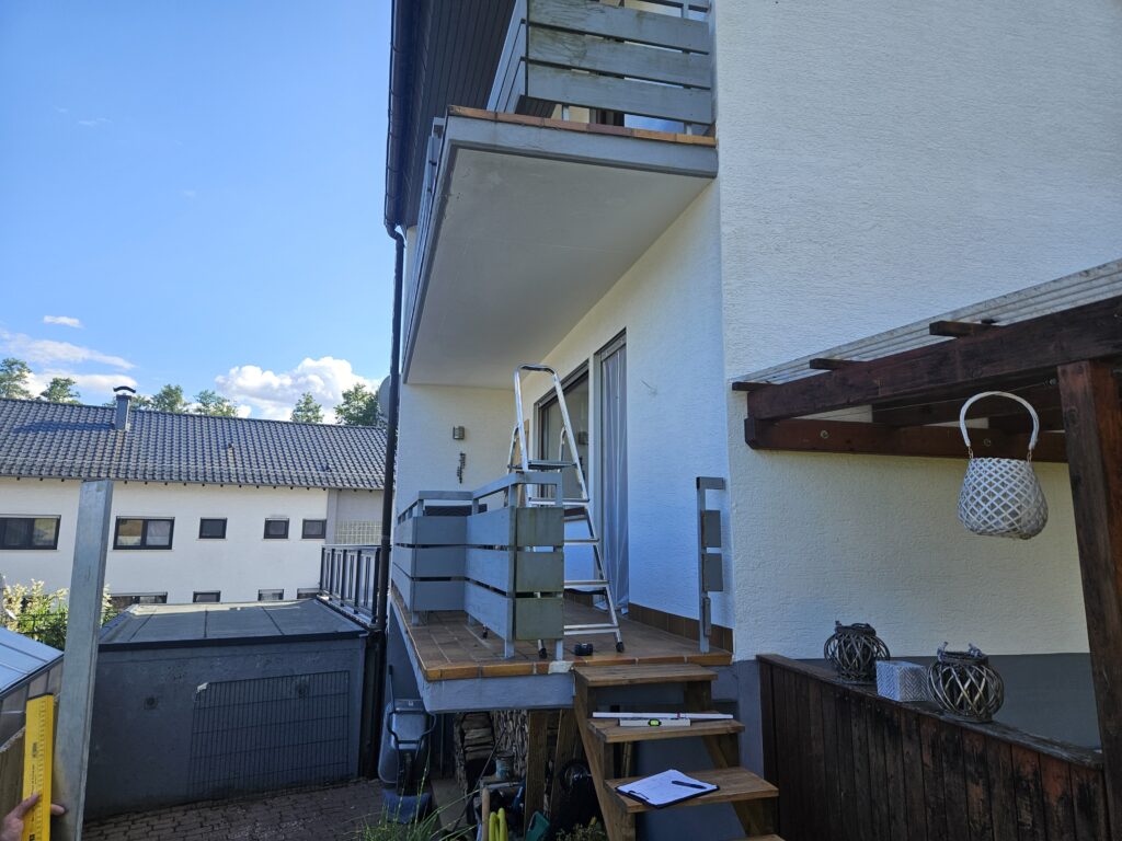Balkon vor der Sanierung mit altem Holzgeländer und Holztreppe